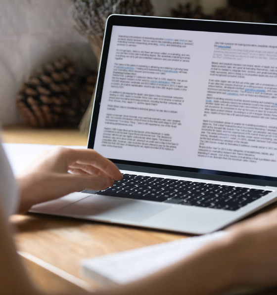 Professional copyediting a business document on a laptop in a modern workspace