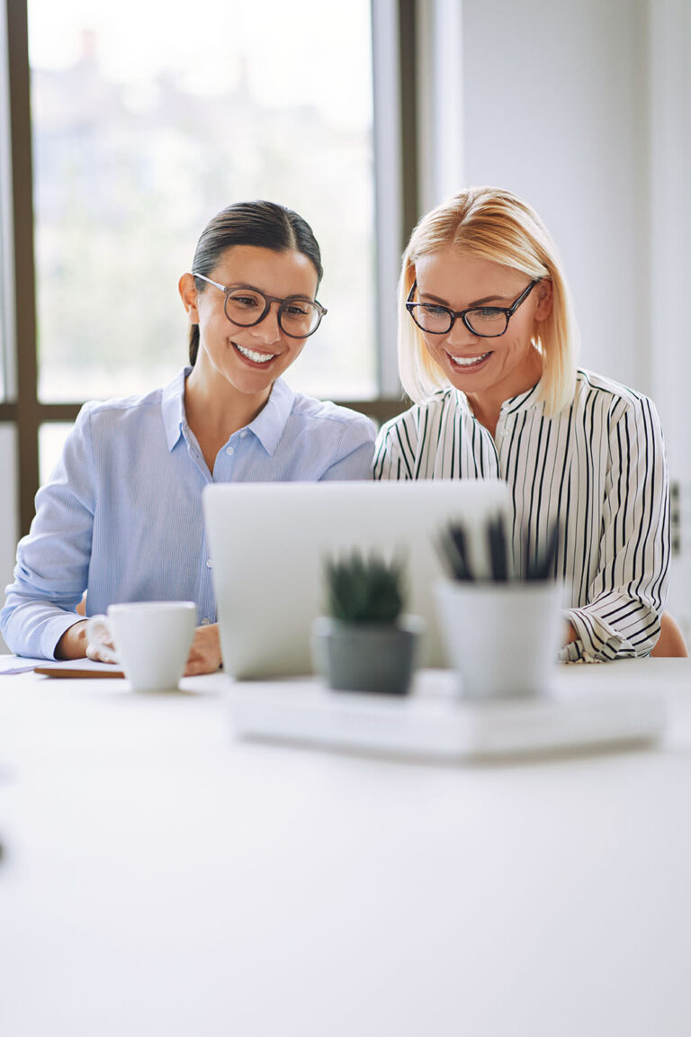 Happy businesswomen reviewing successful award entry content together in the office