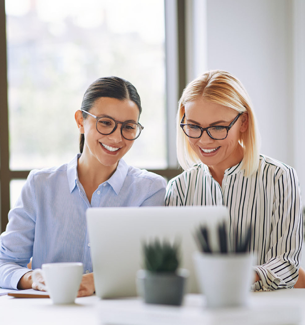 Happy businesswomen reviewing successful award entry content together in the office