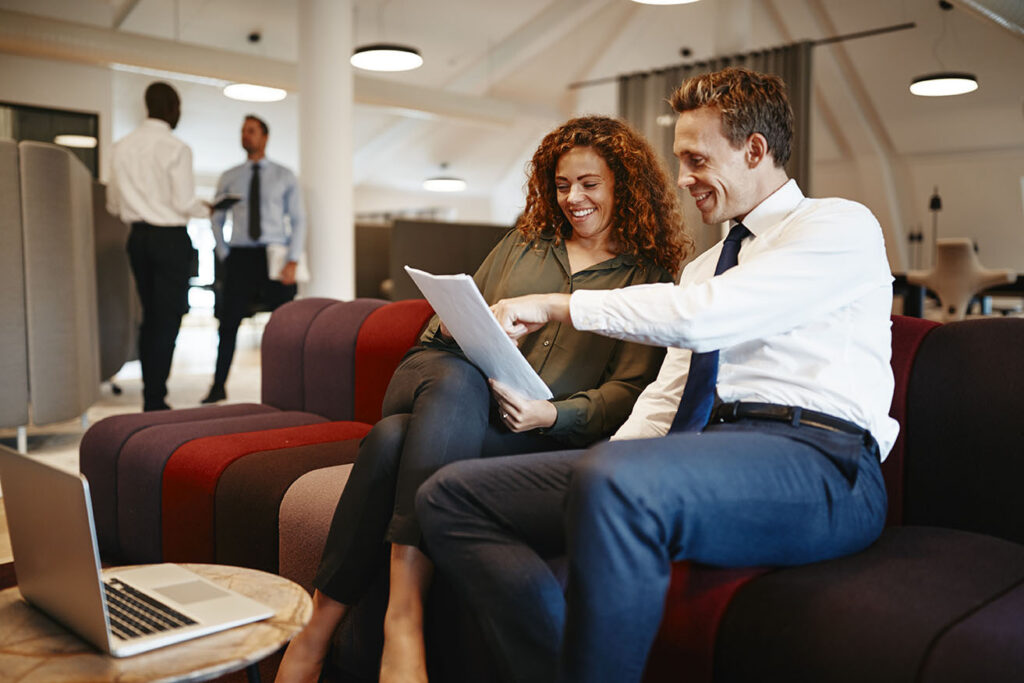 Colleagues discussing awards on a document in a modern office lounge
